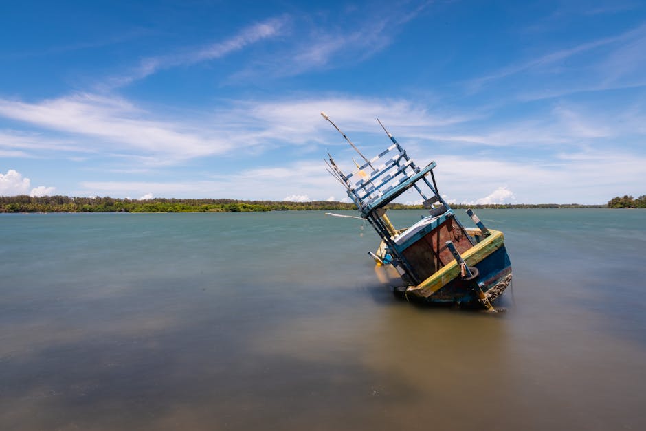 A tilted fishing boat rests in the tranquil waters of Batticaloa Lagoon, Sri Lanka, under a clear blue sky.