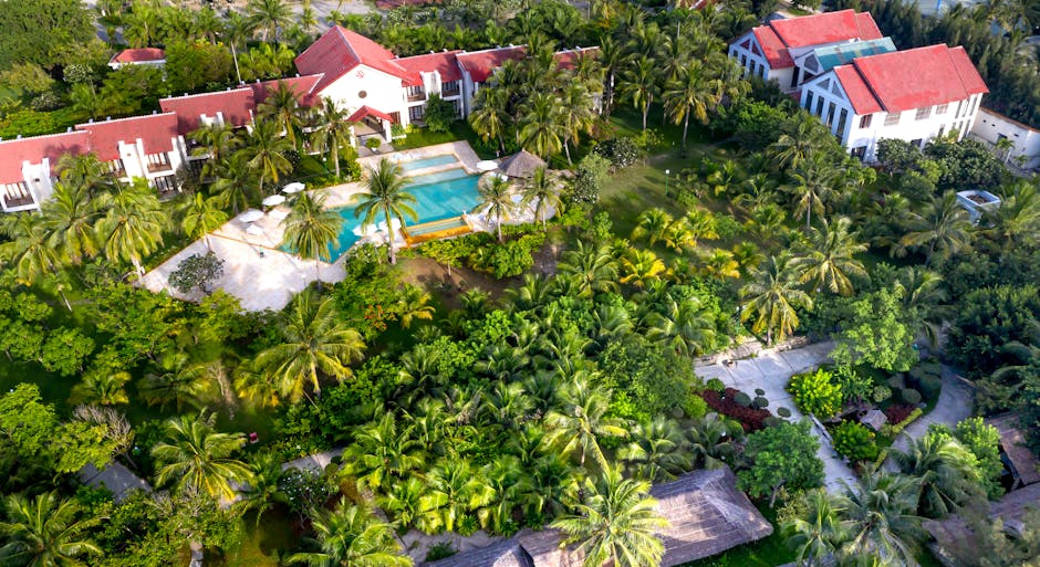 Aerial view of a lush tropical resort featuring a stunning swimming pool and gardens.