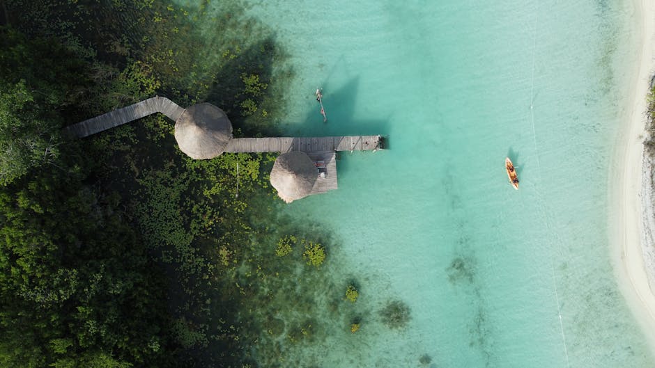 Drone shot of crystal-clear waters with jetty and boat at Bacalar Lagoon, Mexico.