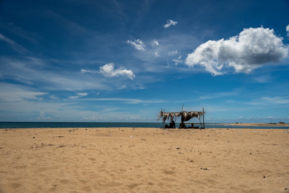 Serene beach with rustic shelter under blue sky in Eastern Sri Lanka.