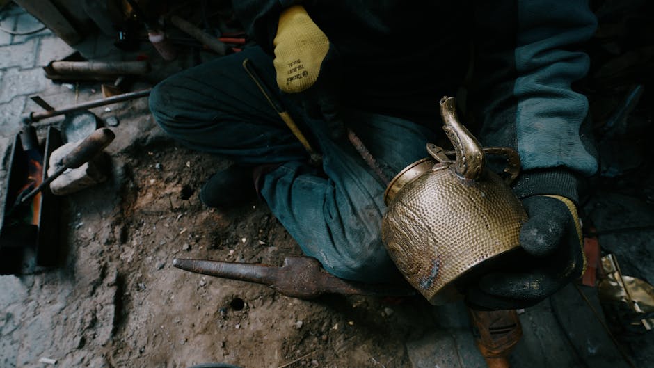 A skilled artisan working on a brass teapot in a traditional workshop, highlighting craftsmanship.