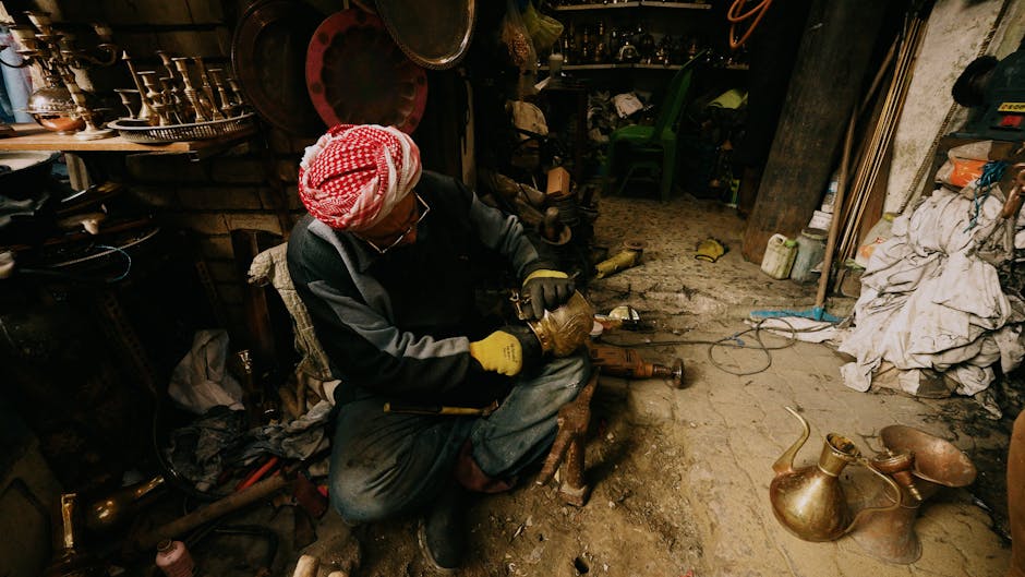Craftsman in a workshop polishing a brass pot, surrounded by rustic tools and decor.